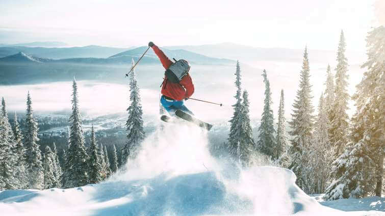 En skidåkare hoppar i en opistad backe under ett test av en röd skidjacka.