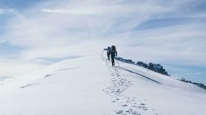 Två vandrare testar värmestrumpor på en vintervandring uppför ett fjäll.